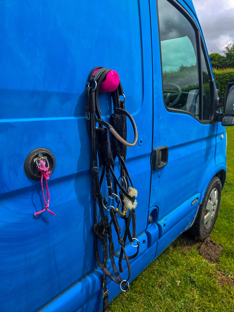StablePin Plus pink magnetic hook mounted on a horsebox cab door holding a diamante browband bridle